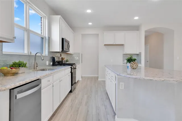 a kitchen with stainless steel appliances granite countertop a sink a stove and cabinets