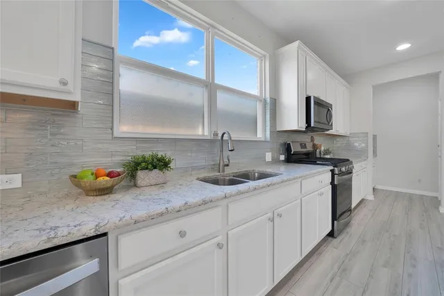 a kitchen with stainless steel appliances granite countertop a sink a stove and cabinets