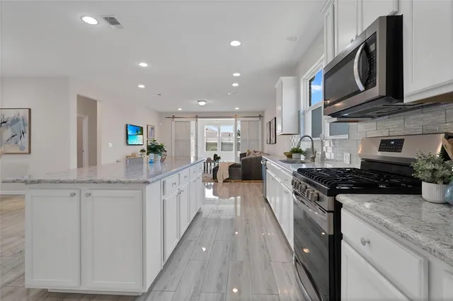 a kitchen with stainless steel appliances granite countertop a stove a sink and a microwave