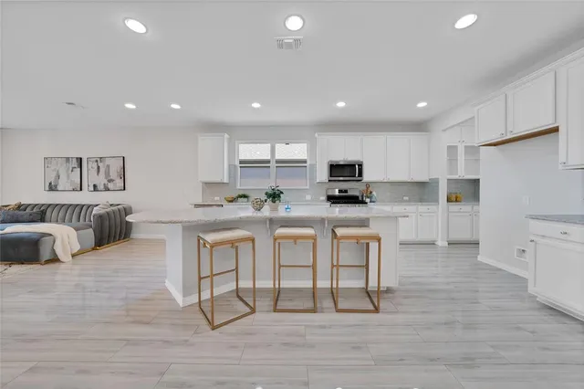 a kitchen with stainless steel appliances granite countertop a table chairs sink refrigerator and cabinets