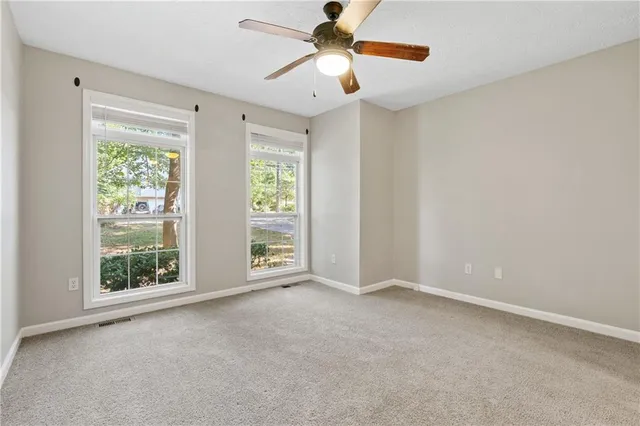 a view of an empty room with window and chandelier fan