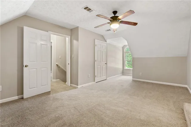 an empty room with chandelier fan and windows