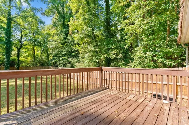a balcony with wooden floor and trees in the back