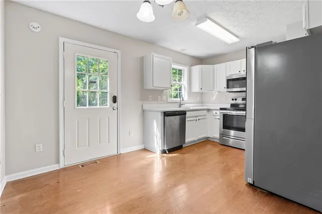 a kitchen with stainless steel appliances granite countertop a stove a sink and a refrigerator with wooden floor