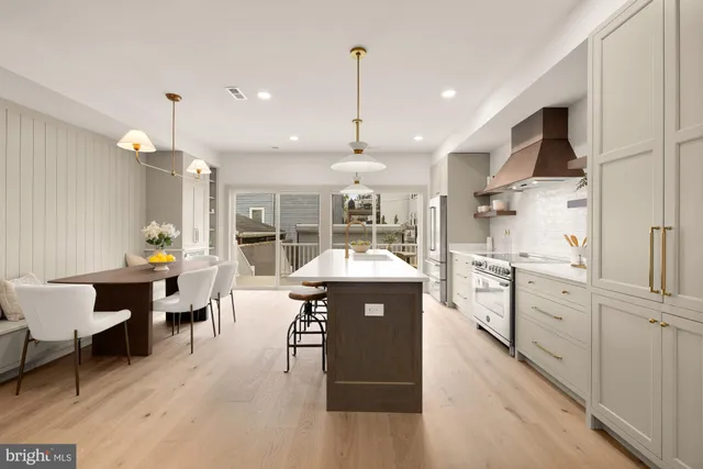 a kitchen with kitchen island a sink a stove a dining table and chairs