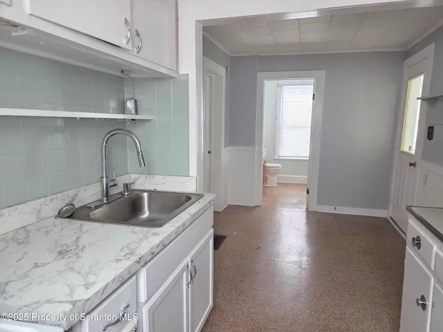 an empty room with windows and chandelier fan