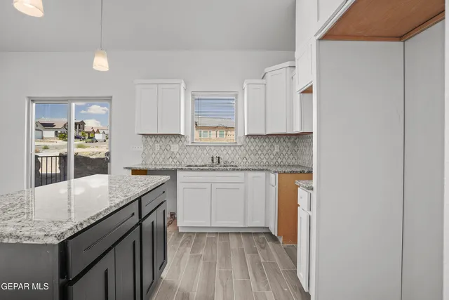 a kitchen with granite countertop a sink and cabinets