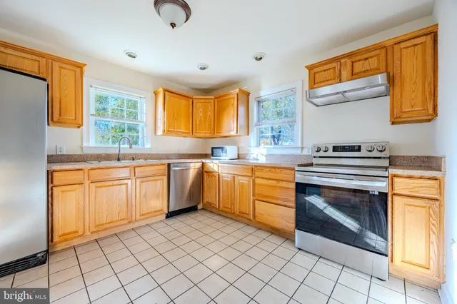 a kitchen with a sink appliances cabinets and a window