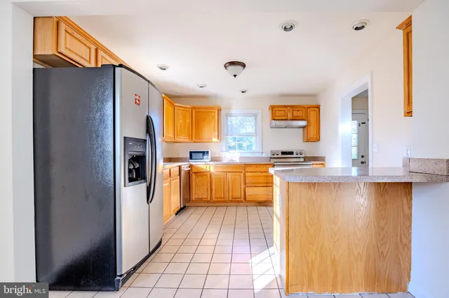 a large kitchen with stainless steel appliances granite countertop a refrigerator and a sink