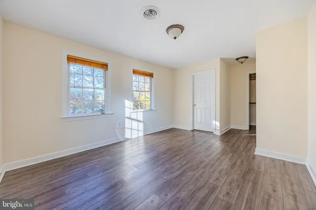 an empty room with wooden floor and windows