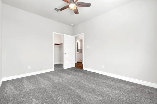 an empty room with a ceiling fan and carpet