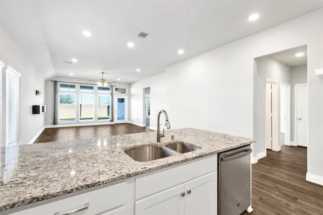 a kitchen with stainless steel appliances granite countertop a sink a counter space and a window
