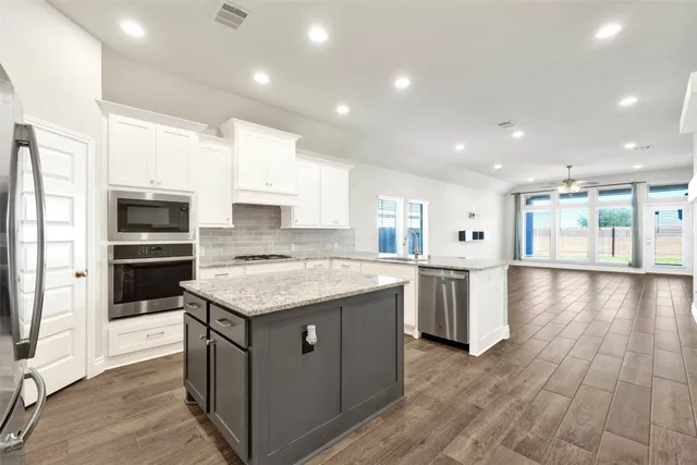 a kitchen with kitchen island granite countertop a stove top oven and refrigerator