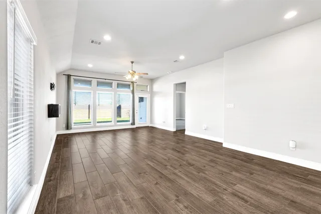 an empty room with wooden floor and windows