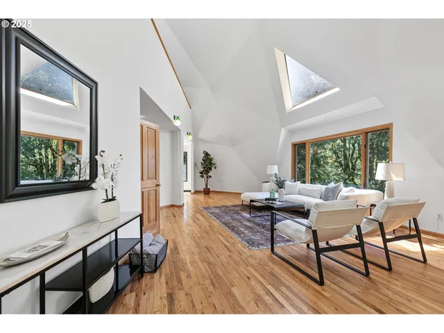 a living room with furniture a large window and wooden floor