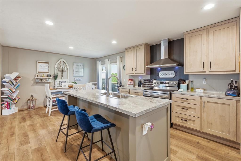 193 Firefly Drive Springtown, TX 76082 - Photo 13 of 32 Spacious kitchen featuring an expansive center island with an undermount sink, light-toned wood-finish flooring, recessed lighting, and stainless steel appliances