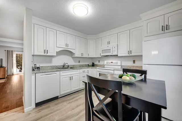 a kitchen with stainless steel appliances granite countertop a stove a sink dishwasher and white cabinets with wooden floor