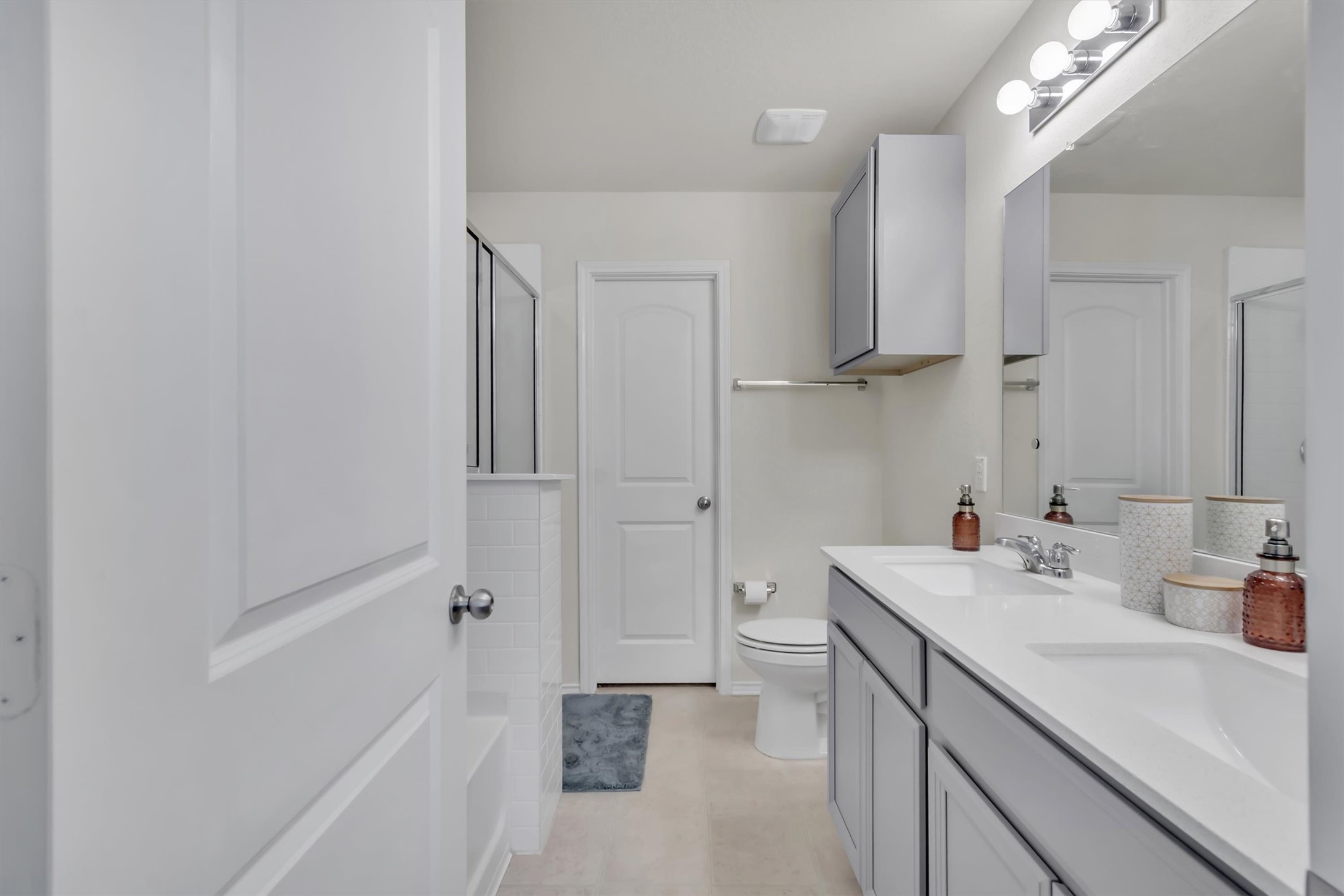 11701 Jackson Falls Way Manor, TX 78653 - Photo 18 of 40 A well-lit primary bathroom features a dual vanity, sleek cabinets, and a convenient shower.
