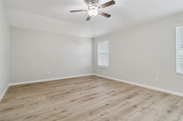 a view of an empty room with window and wooden floor