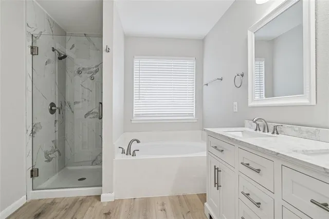 a bathroom with a granite countertop sink a mirror bathtub and shower