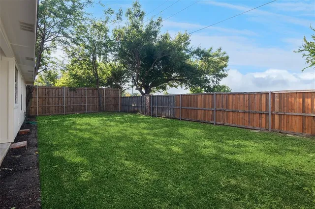 a view of a yard with a fence and trees
