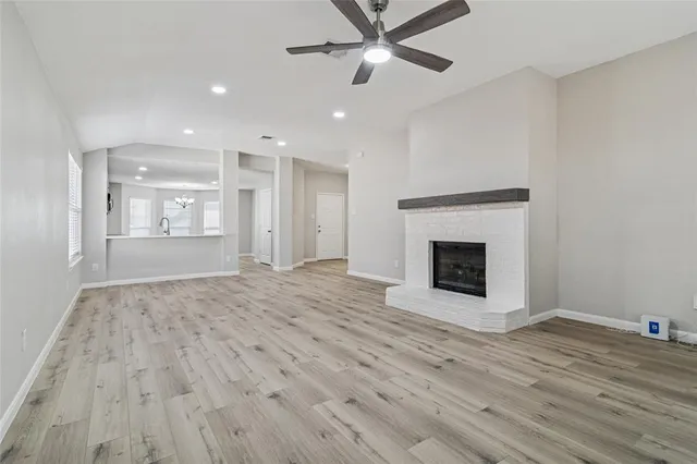 a view of an empty room with wooden floor fireplace and a window