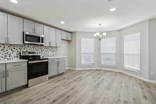 a kitchen with granite countertop a stove a sink dishwasher a microwave oven and a refrigerator with wooden floor