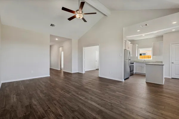 a view of an empty room with a window and wooden floor