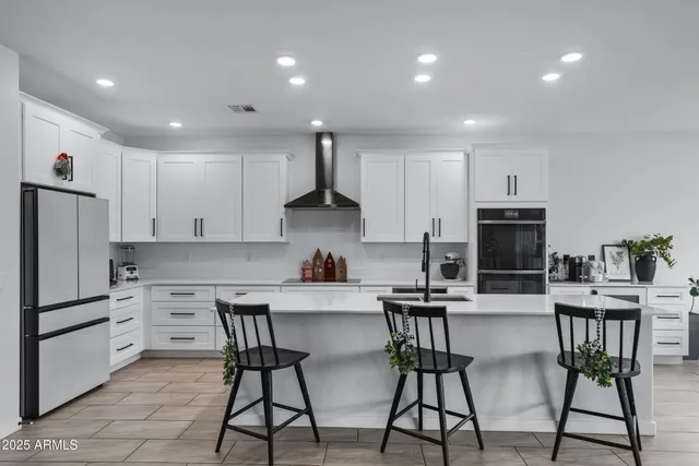 a kitchen with stainless steel appliances kitchen island granite countertop a dining table chairs refrigerator and sink