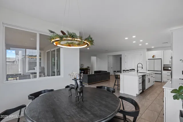 a kitchen with stainless steel appliances kitchen island granite countertop a table chairs and a refrigerator