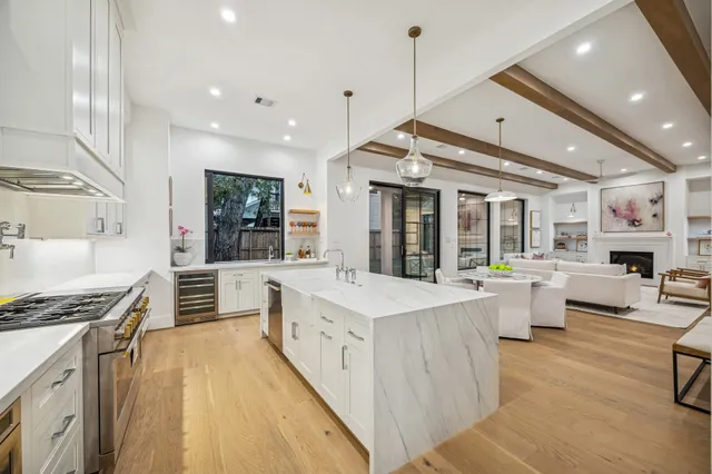 a large white kitchen with granite countertop a sink and white cabinets next to a large window