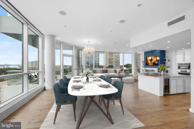 a living room with couches a coffee table and kitchen view with wooden floor