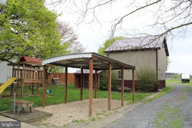 a view of a barn with a yard table and chairs under an umbrella