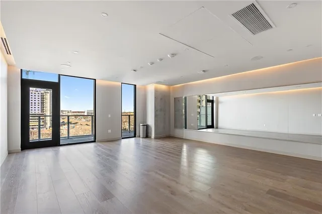 a view of an empty room with window and wooden floor