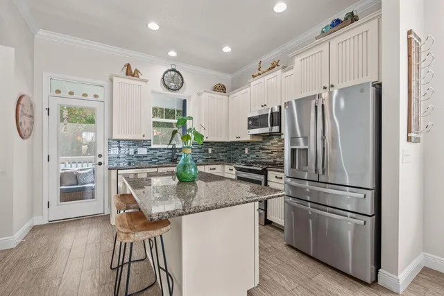 a kitchen with stainless steel appliances granite countertop a refrigerator a stove a sink and a dining table with wooden floor