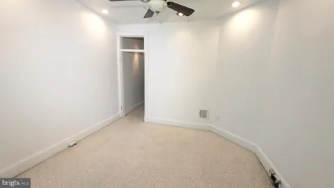 an empty room with a ceiling fan and carpet