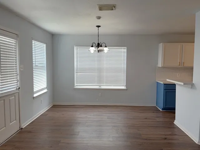 an empty room with wooden floor windows and cabinet