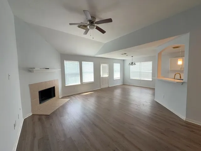 a view of a livingroom with wooden floor a fireplace and windows