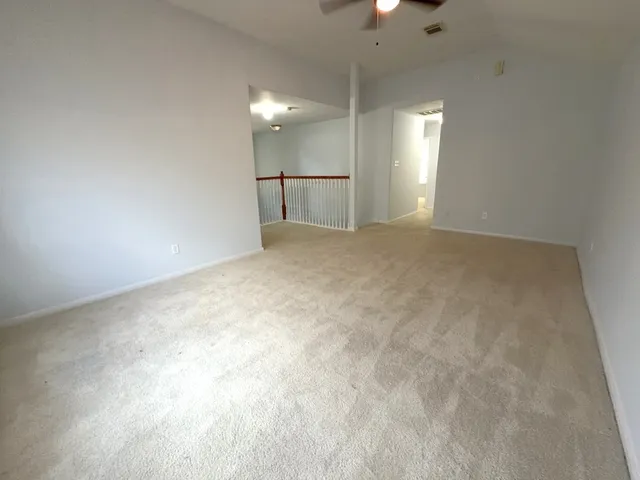 an empty room with a chandelier fan and windows
