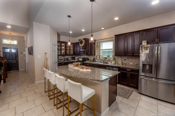 a kitchen with stainless steel appliances granite countertop wooden cabinets a refrigerator a sink a stove a microwave and island