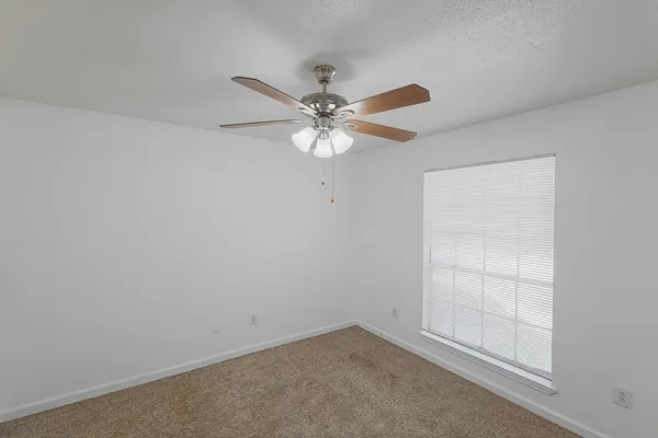an empty room with a ceiling fan and a window