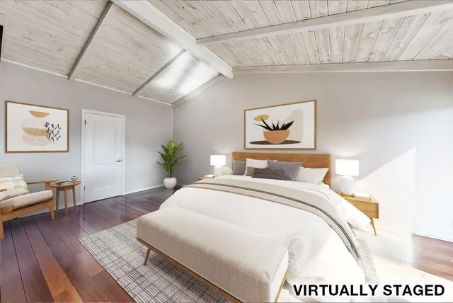 a bedroom with a large bed a painting on the wall and a wooden floor