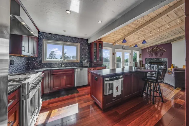 a kitchen with stainless steel appliances granite countertop wooden floors a stove and a sink