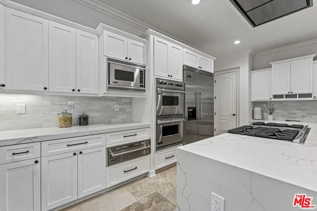 a kitchen with stainless steel appliances granite countertop a stove a sink dishwasher and a flat screen tv