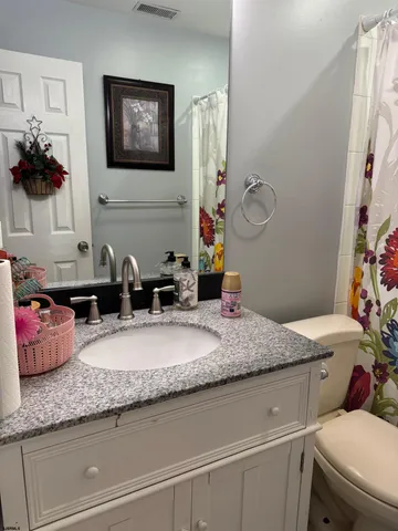 a bathroom with a granite countertop sink a mirror and a toilet