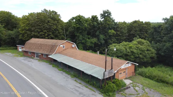 a view of a white house with a yard plants and large trees