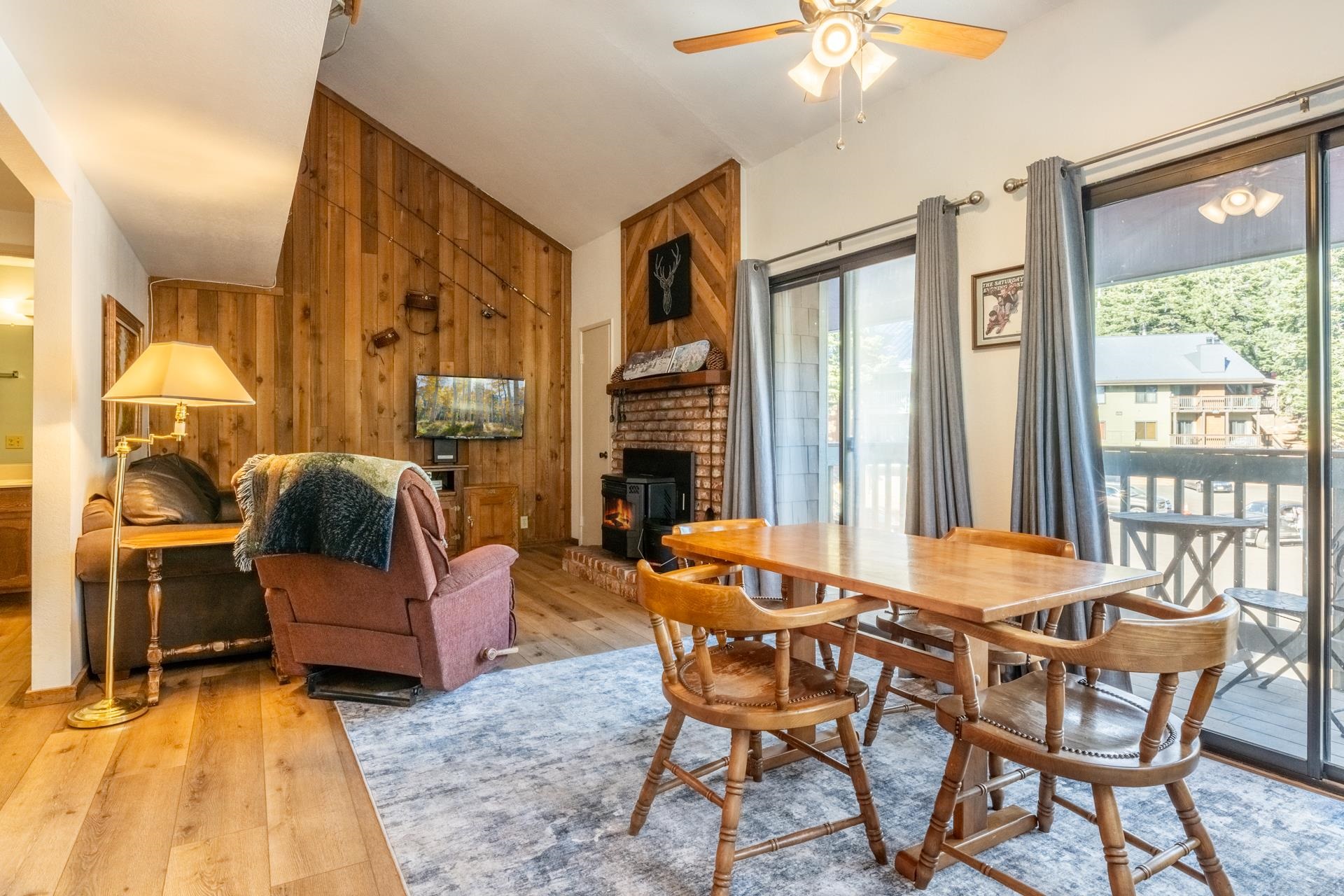 Dining area with wood walls, vaulted ceiling, hardwood / wood-style flooring, a wood stove, and ceiling fan