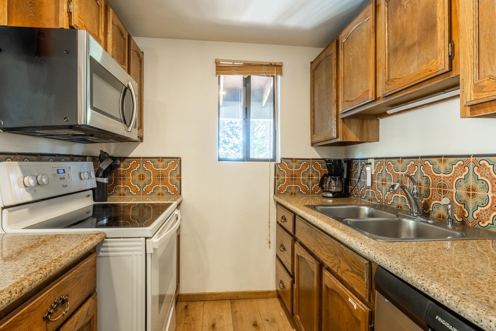 153 Lake Mary Road, Unit 132 Mammoth Lakes, CA 93546 - Photo 8 of 20 Kitchen featuring appliances with stainless steel finishes, brown cabinets, decorative backsplash, and light wood-style flooring