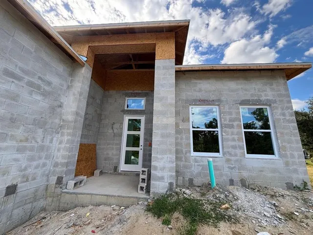 a front view of a stone house with plants