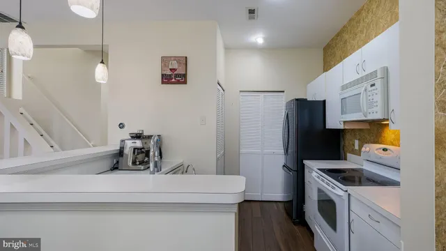 a kitchen with stainless steel appliances a refrigerator a sink and white cabinets